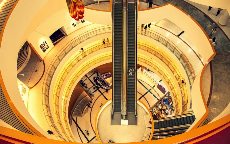 Shopping mall atrium with escalators and storefronts